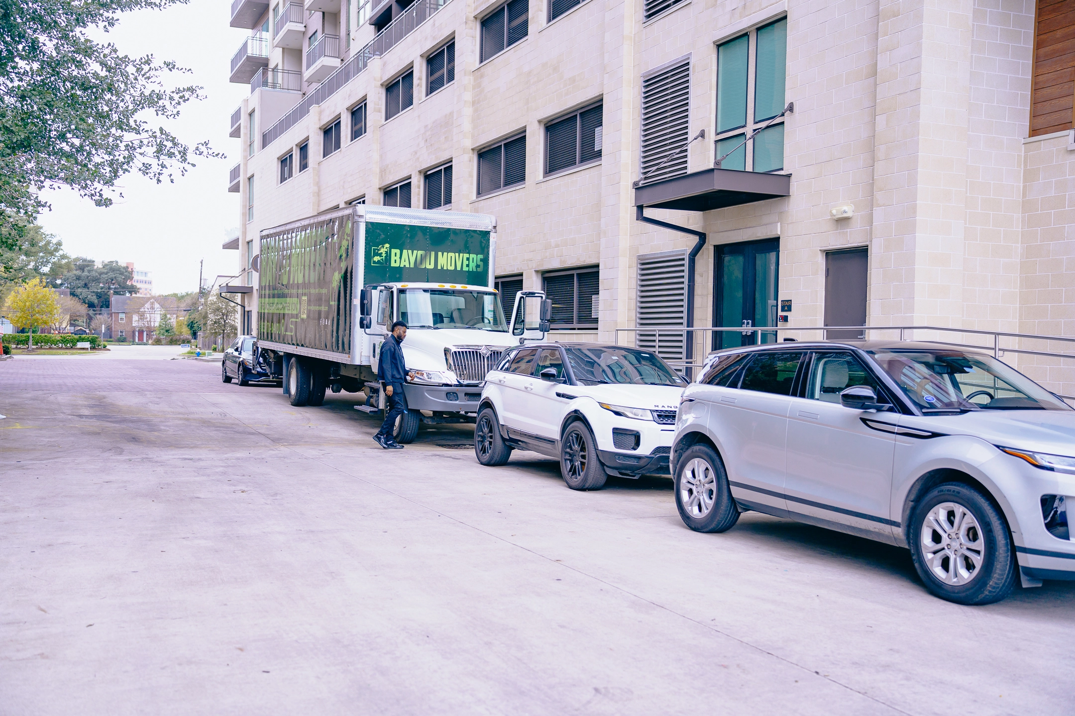Bayou Movers truck staged beside a multi-story Houston apartment building