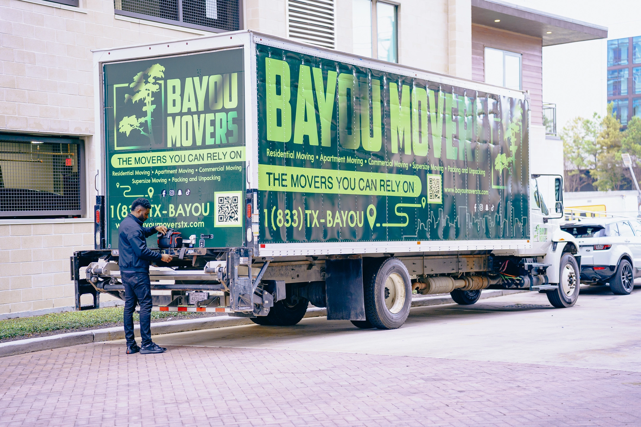Bayou Movers commercial moving truck staged beside a large Houston building