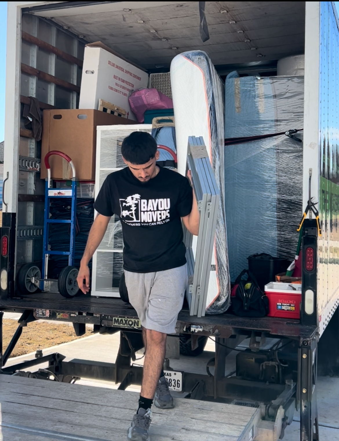 Bayou Movers crew member at a truck loaded with protected furniture