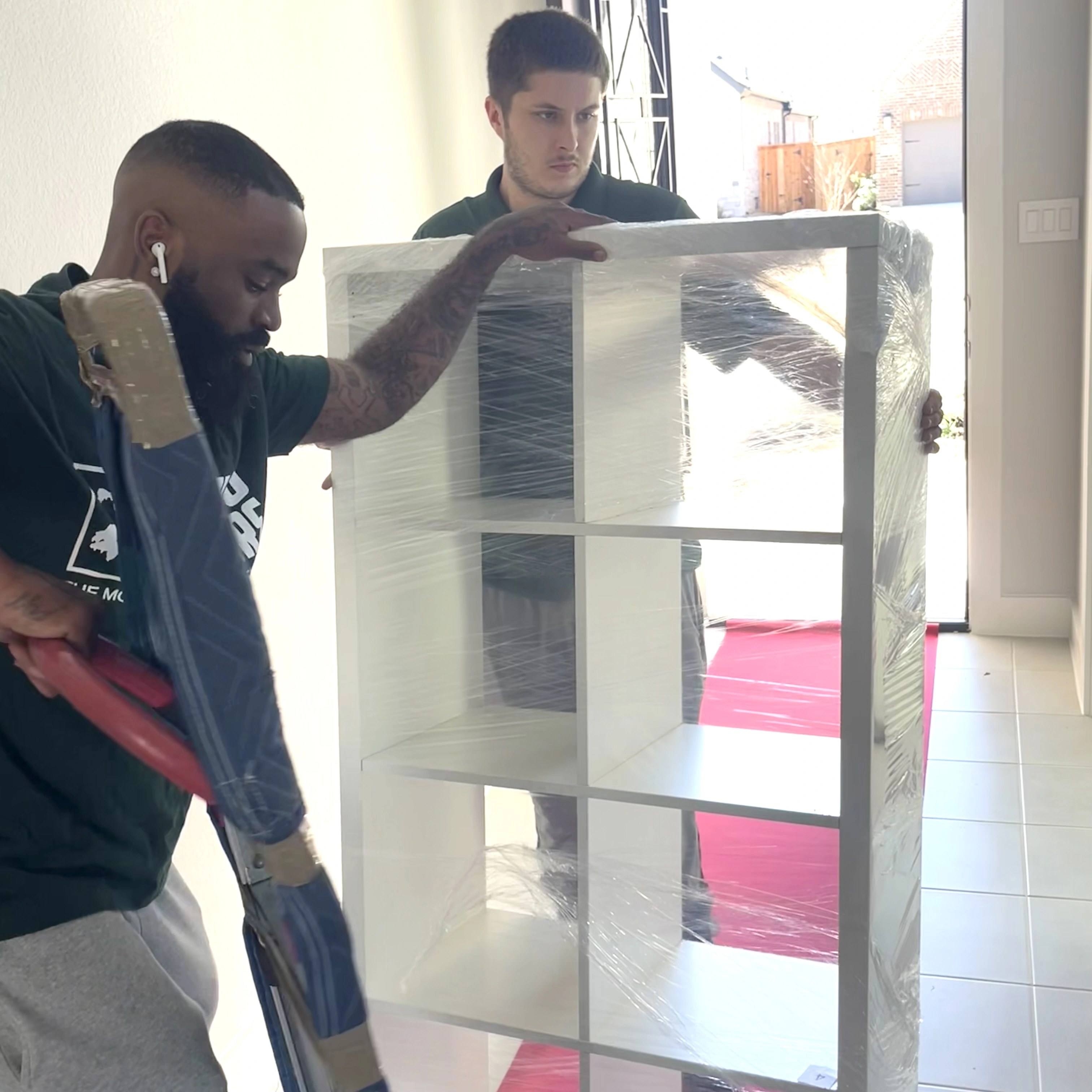Two Bayou Movers crew members carrying a tall shelving unit