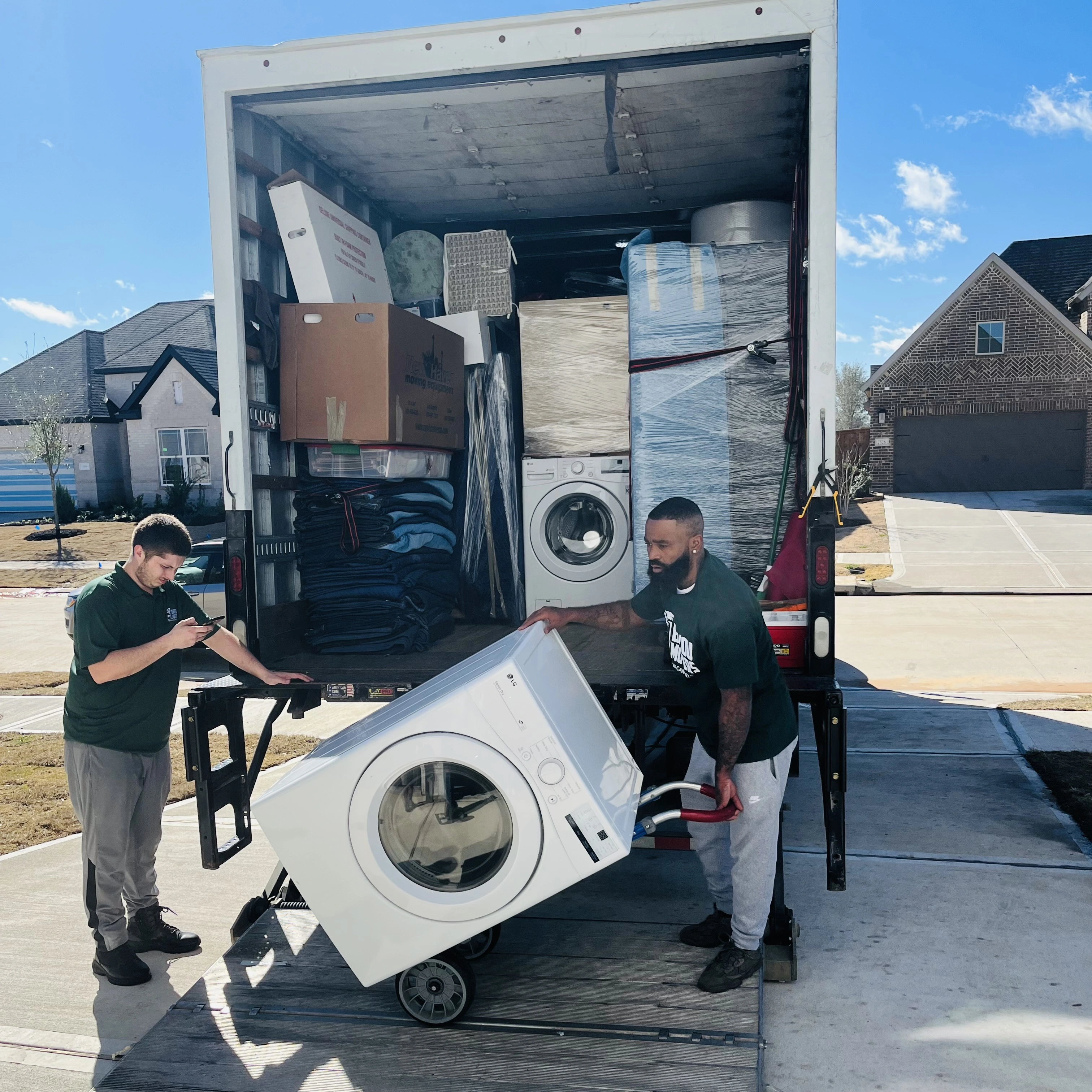 Two Bayou Movers crew members handling a large appliance at the truck
