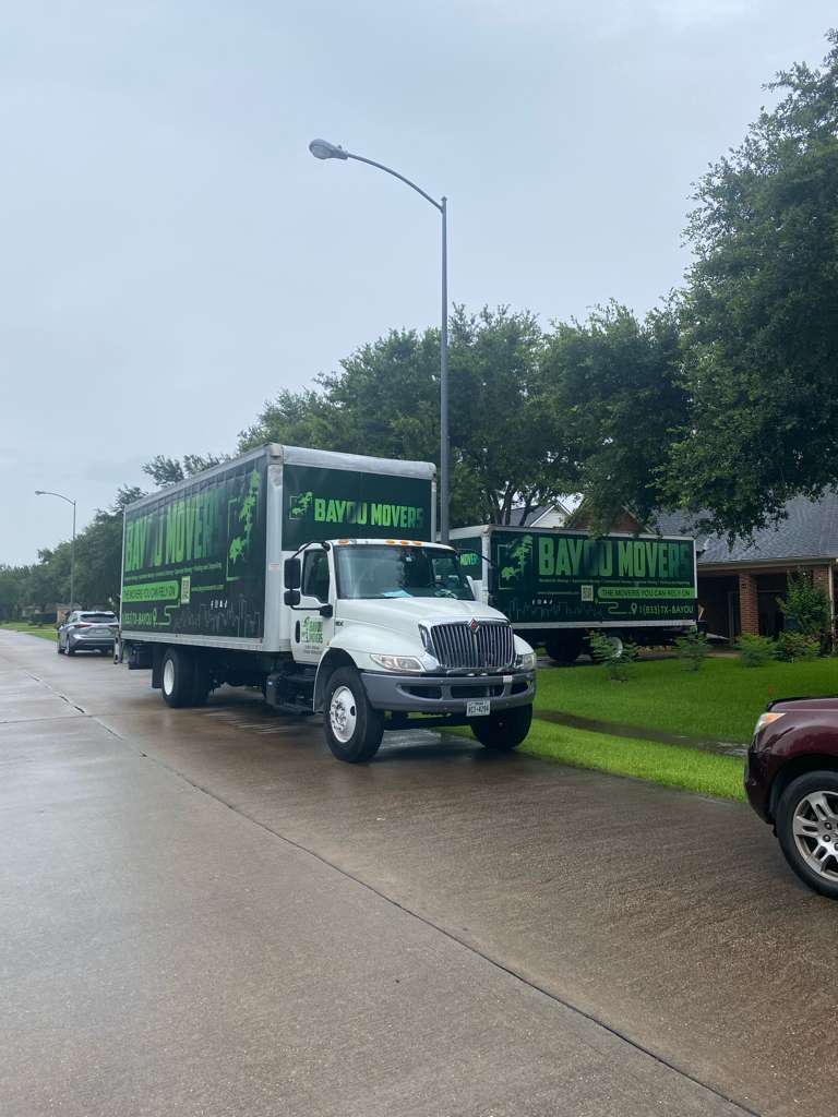 Two Bayou Movers trucks parked on a residential street